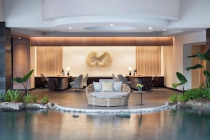 A modern lobby with a central seating area, a reception desk, and a decorative wall piece.