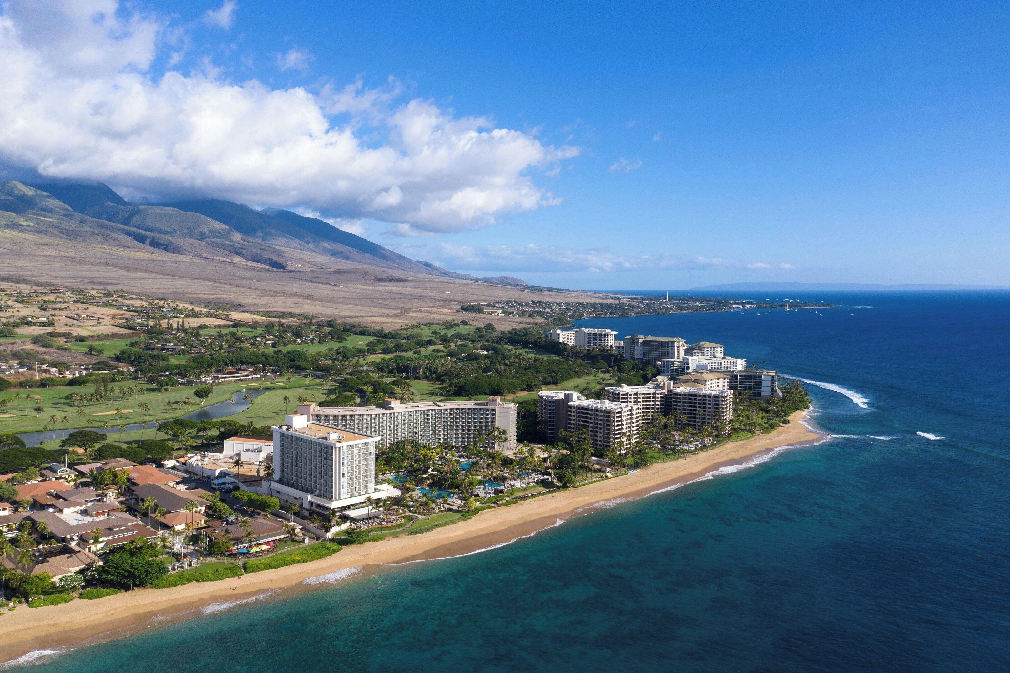A coastal resort with beachfront hotels, a golf course, and a view of the ocean.