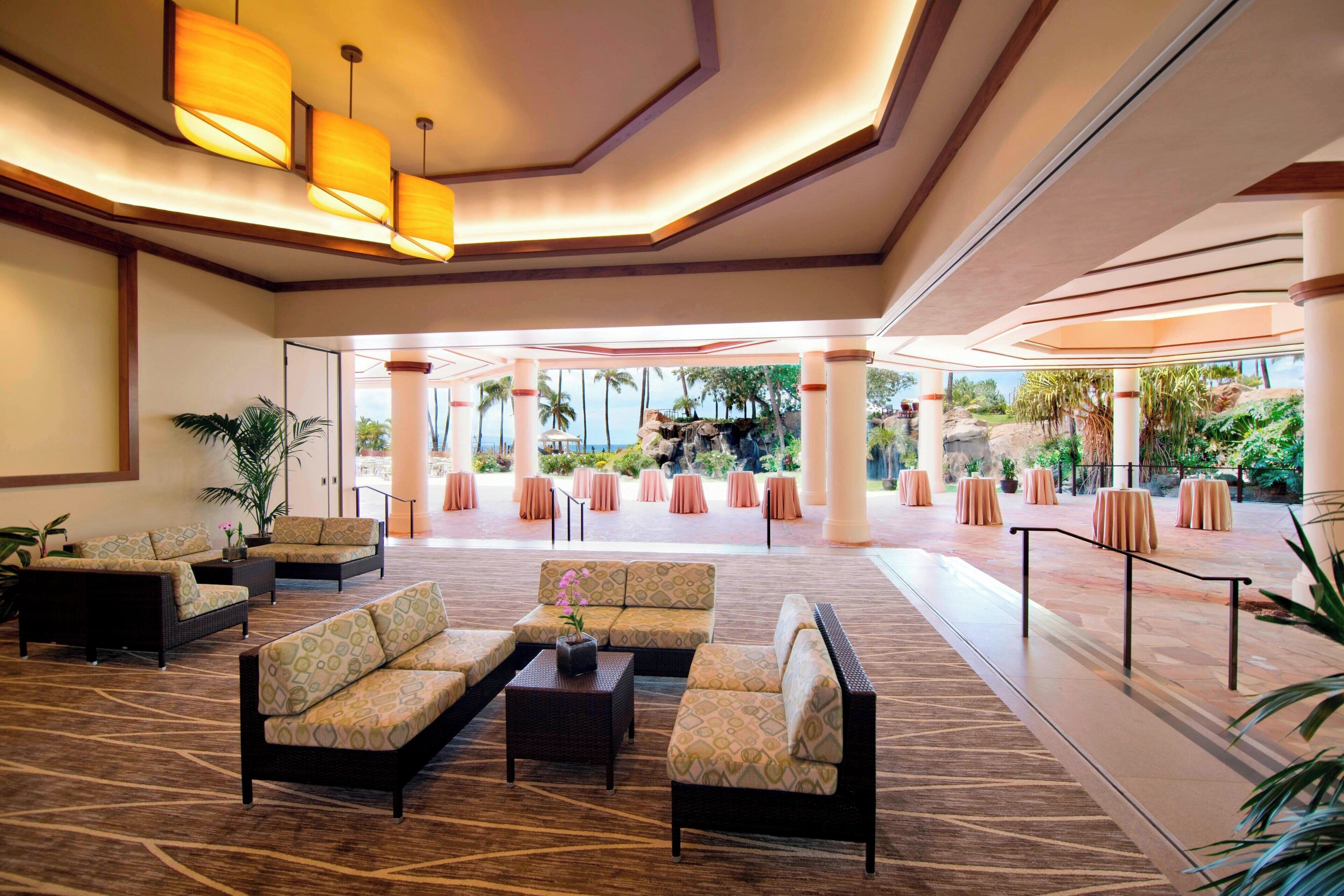 Eine großzügige Lobby mit modernem Design, ausgestattet mit Sofas, einem Couchtisch und Blick auf einen tropischen Garten.