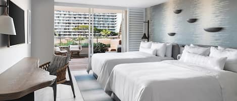 Ett hotellrum med två sängar, ett skrivbord och utsikt över en hög byggnad och ett utomhusområde.