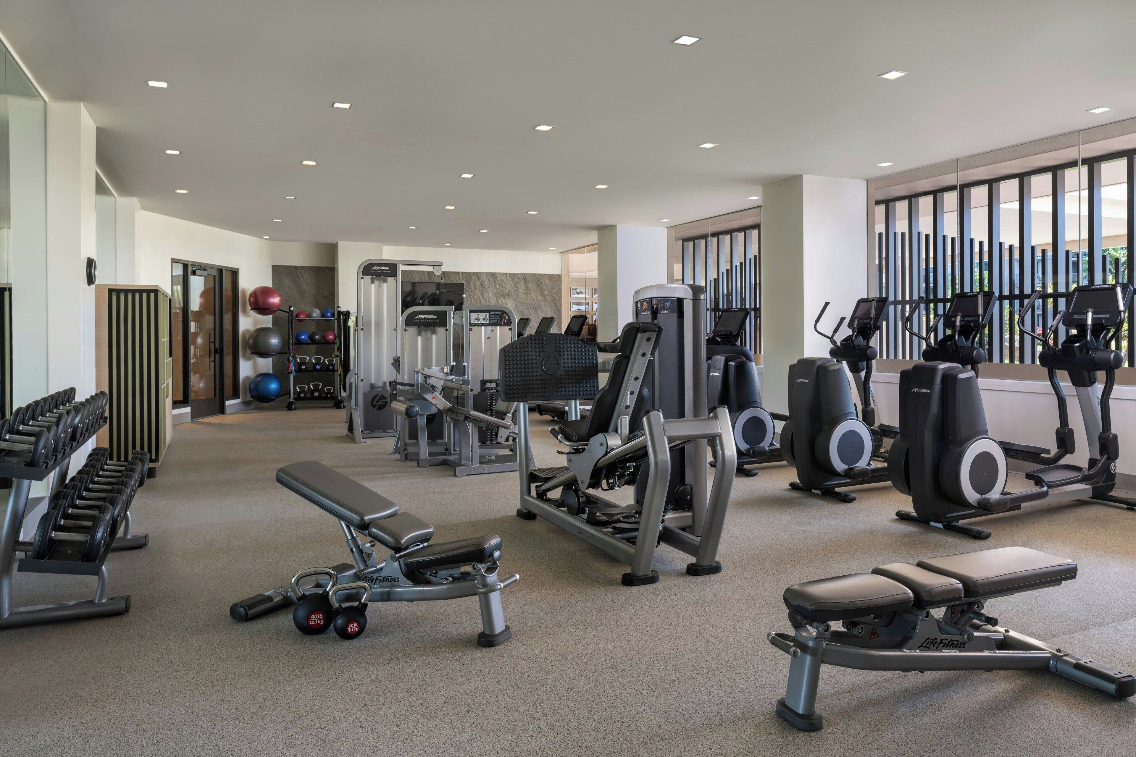 A modern gym with various exercise equipment, including treadmills, weight machines, and free weights.