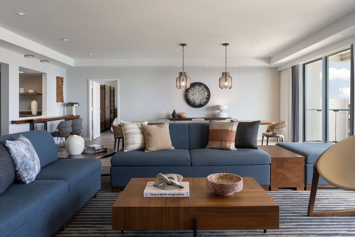 Una sala de estar moderna con un sofá azul, una mesa de centro de madera y lámparas colgantes.