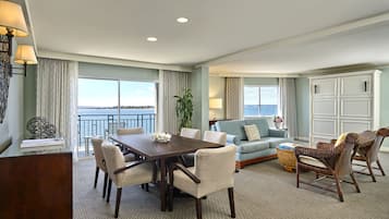 A spacious living room with a dining area, large windows with a view, and a balcony.