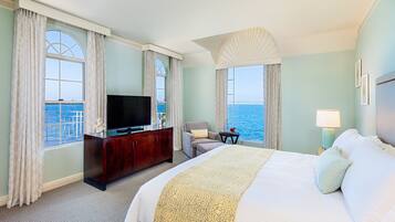 Una habitación de hotel con una cama grande, televisión, escritorio y vista al mar.