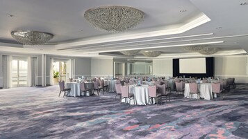 A conference room with round tables, chairs, and a large screen.
