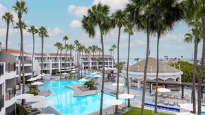 A resort with a large swimming pool surrounded by palm trees and lounge chairs. - Loews Coronado Bay Resort (Coronado)