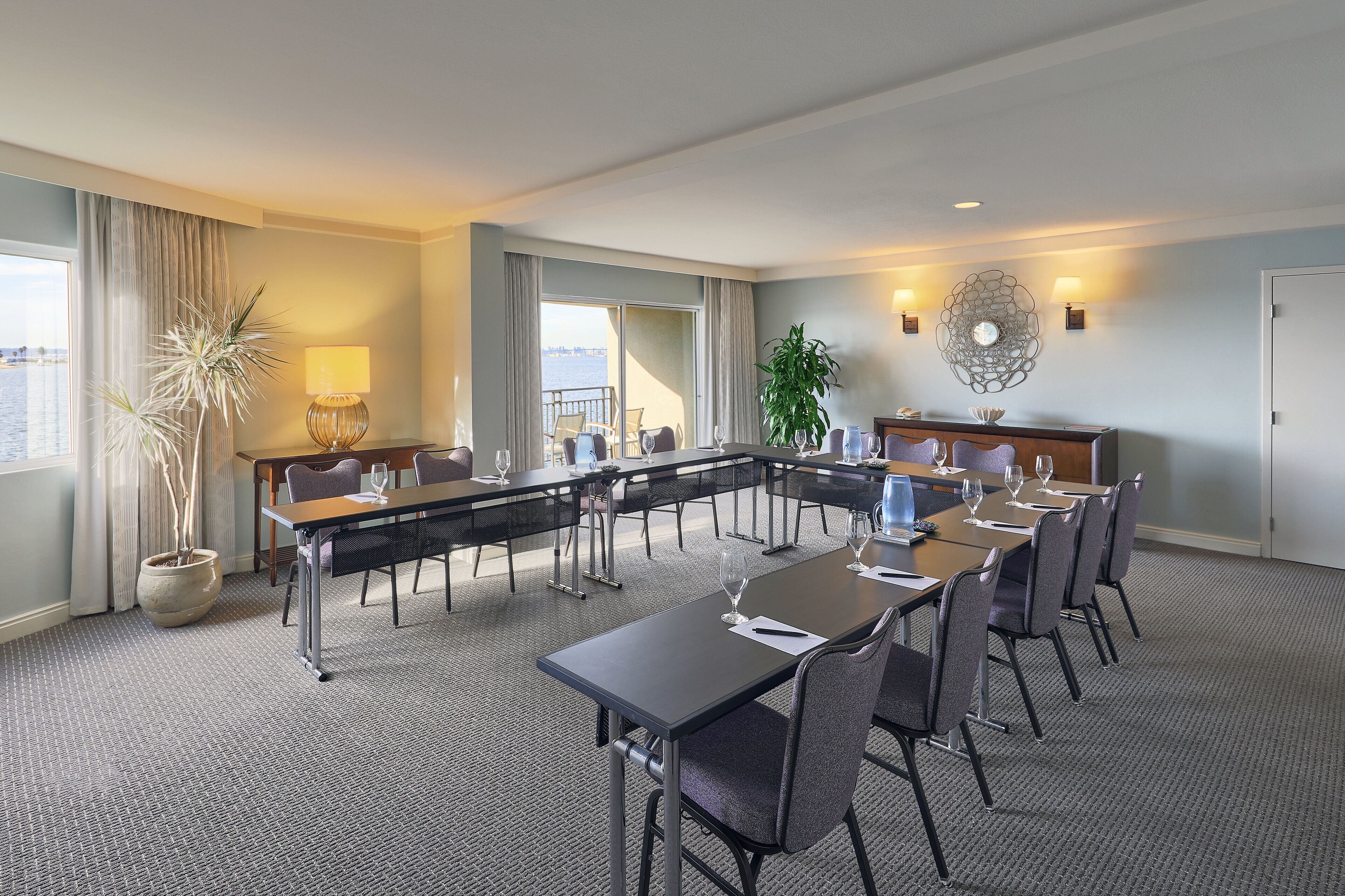 A conference room with a long table, chairs, and a potted plant.