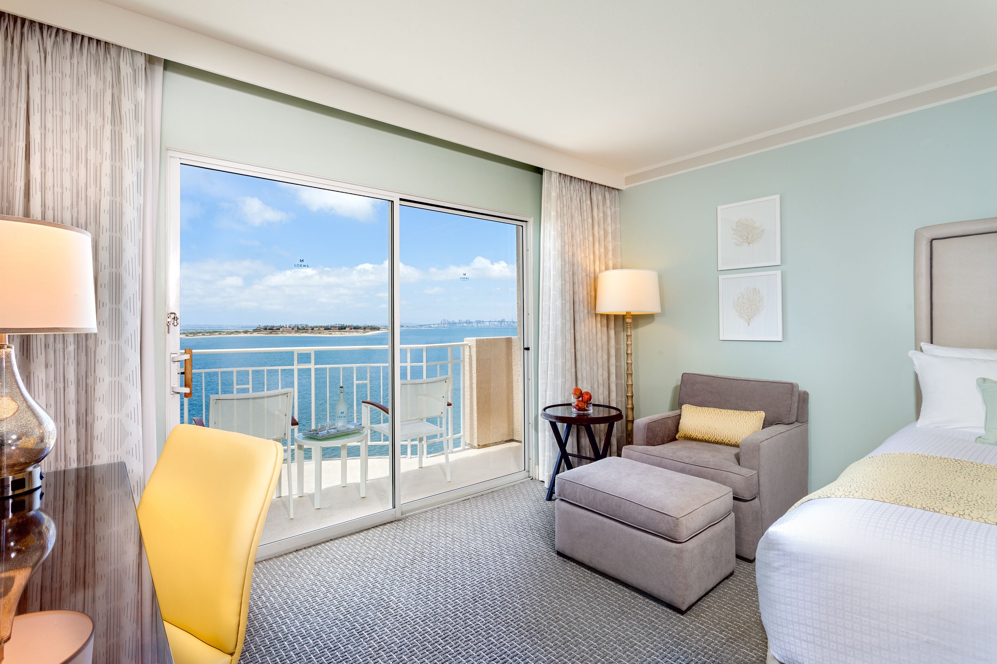 Ein Hotelzimmer mit Balkon, einem Bett, einer Couch, einem Sessel und einem kleinen Tisch.