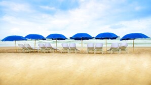 A beach with rows of white lounge chairs and blue umbrellas. - Loews Coronado Bay Resort (Coronado)