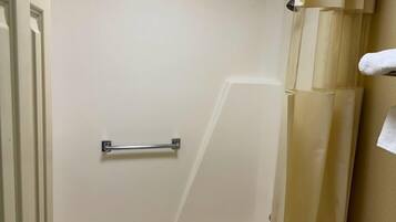 Un baño con bañera, cortina de ducha, toallero y inodoro.