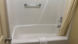 A white bathtub with a towel, a shower curtain, and a grab bar. - Somatel Goodlettsville (Goodlettsville)