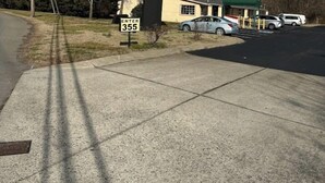 A motel sign with a green roof and a parking lot with several cars. - Somatel Goodlettsville (Goodlettsville)