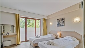 A hotel room with two beds, a desk, a mirror, and a window with curtains. - Sleep & Go Brussels South (St. Genesius-Rode)