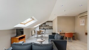A modern apartment with a loft bedroom, a dining area, and a living room with a sofa and a TV. - Sleep & Go Brussels South (St. Genesius-Rode)