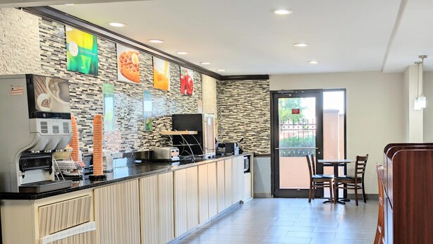A modern kitchen area with a coffee machine, a microwave, and a toaster. There is a seating area with a table and chairs. - Quality Inn DFW Airport North (Irving)