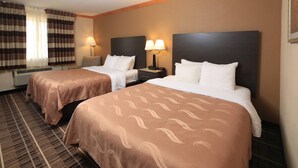 A hotel room with two beds, a window with curtains, a lamp, and a carpeted floor. - Quality Inn DFW Airport North (Irving)