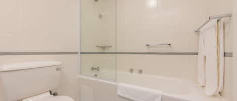 A bathroom with a toilet, a glass-enclosed shower, and a bathtub.