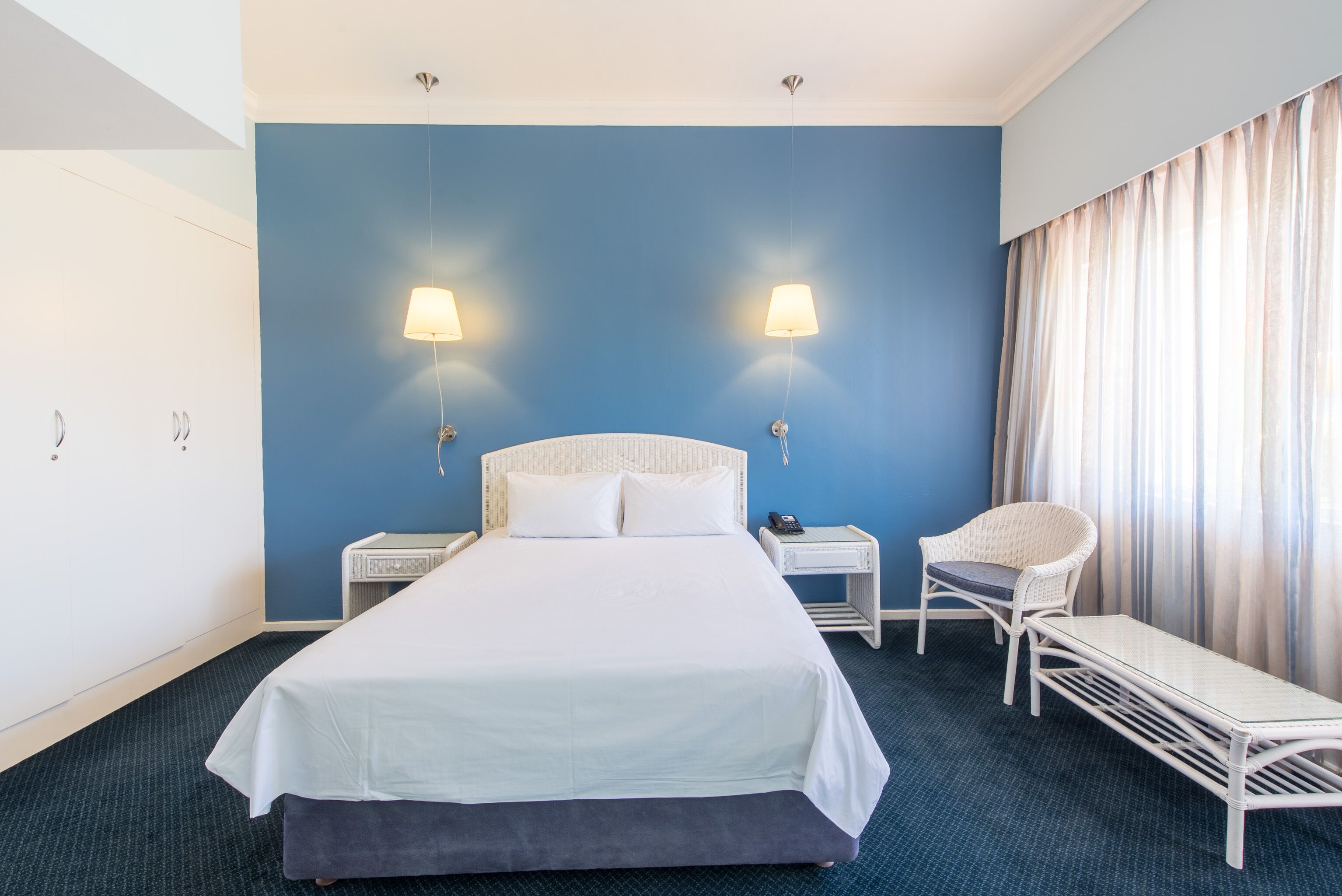 A hotel room with a large bed, two bedside tables, a chair, and a desk.