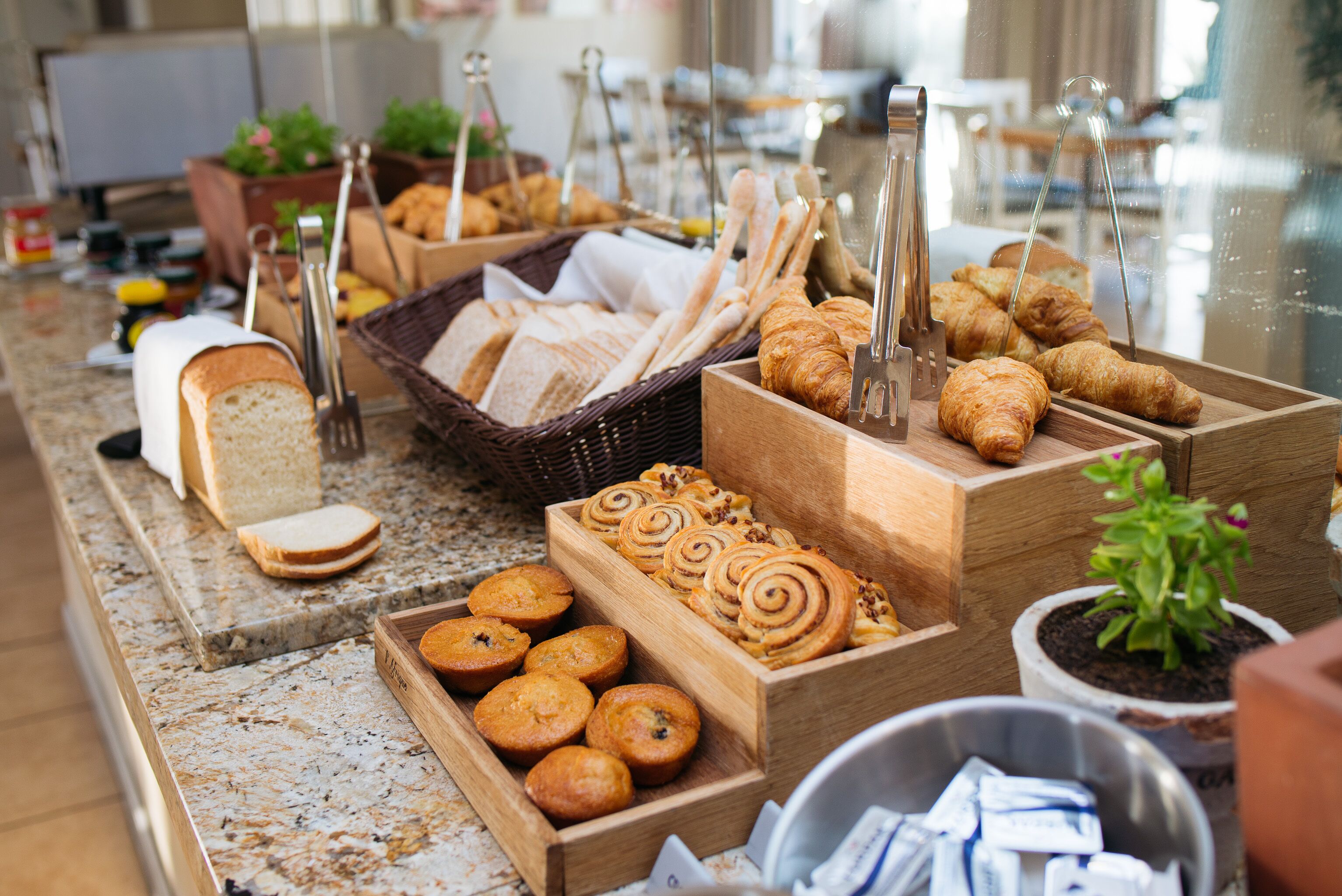 Buffet com diversos produtos de panificação, incluindo pão, doces e muffins.
