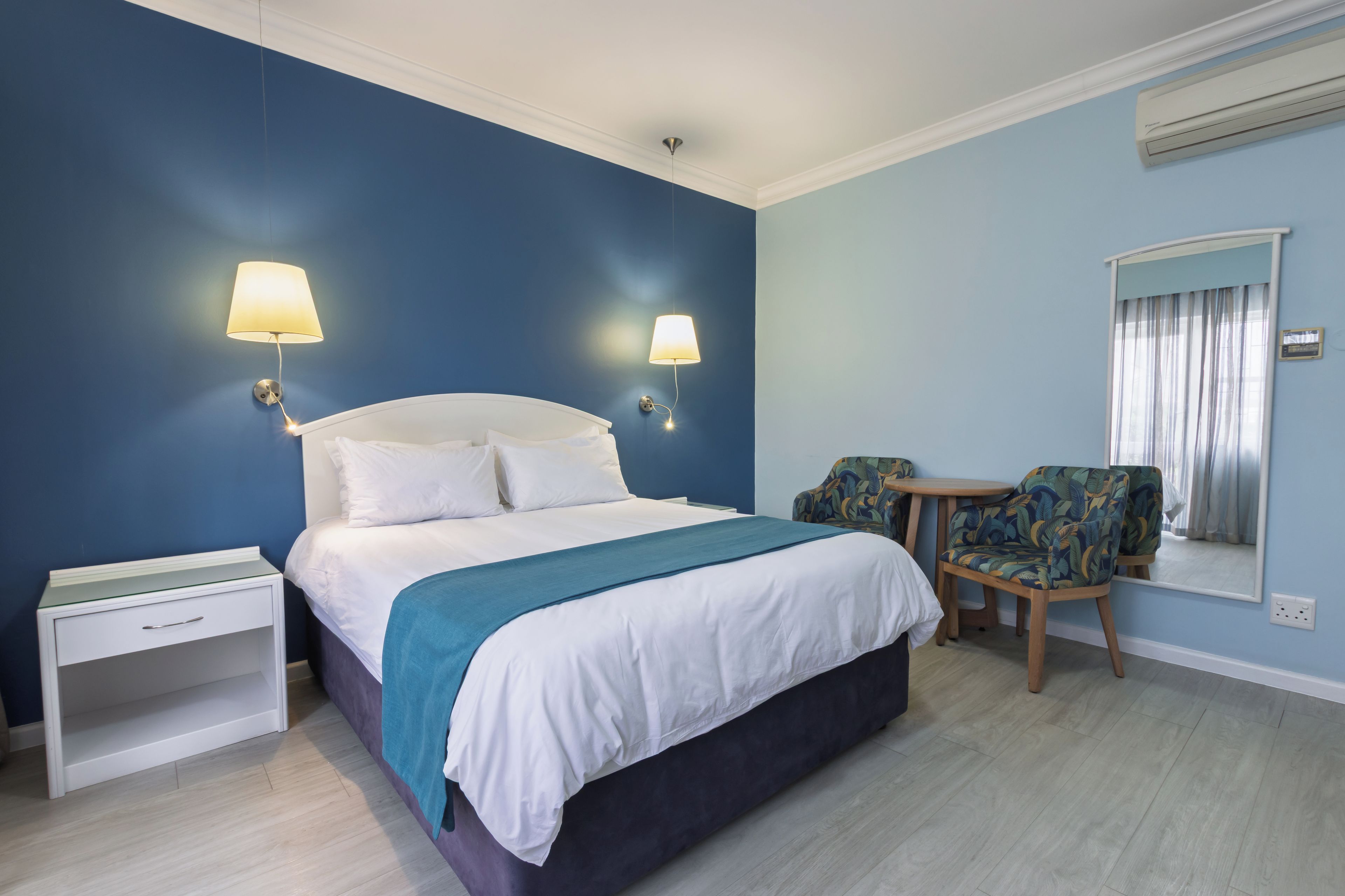 Una camera d'albergo con un letto, comodini, una sedia e un tavolino.