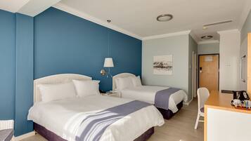 A hotel room with two beds, a desk, a chair, and a painting on the wall.