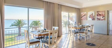 A spacious dining area with a view of the sea, large windows, and a balcony.