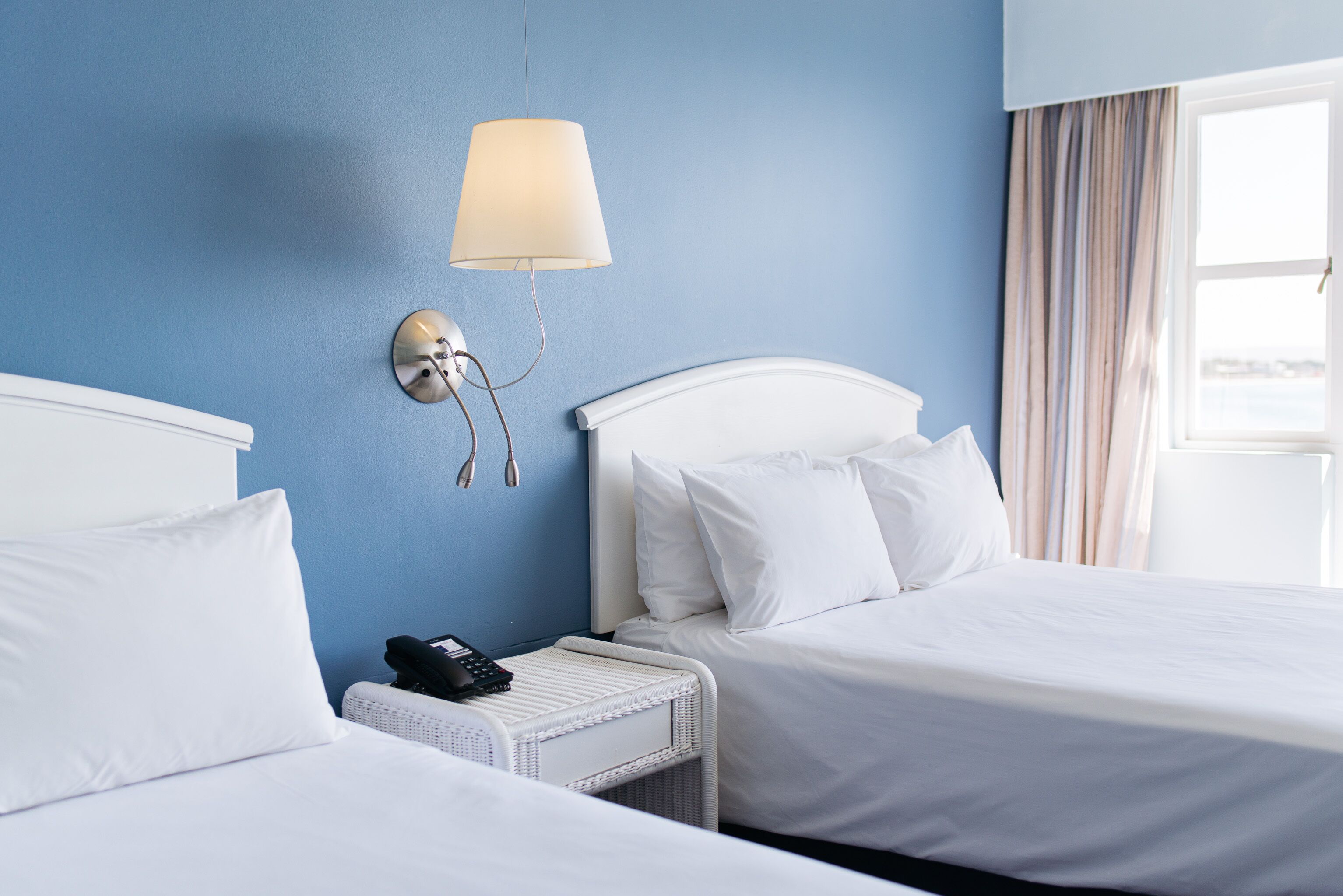 Habitació d'hotel amb dos llits, una taula de nit amb una làmpada i un telèfon.