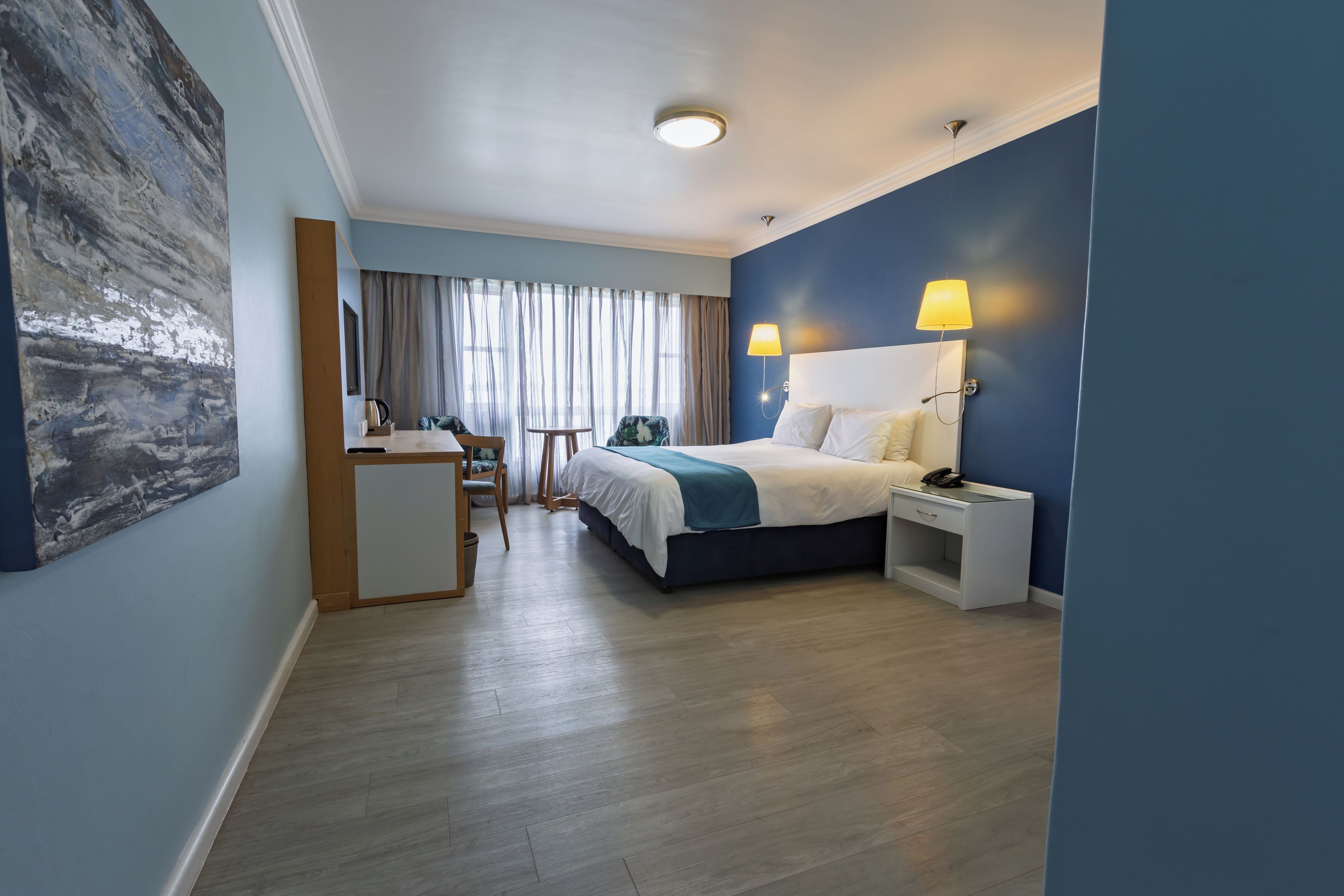 Une chambre d’hôtel comprenant un lit, des tables de chevet, un bureau et une chaise.