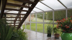 A conservatory with a wooden staircase, potted plants, and a view of a grassy area. - ibis Montbeliard (Montbeliard)