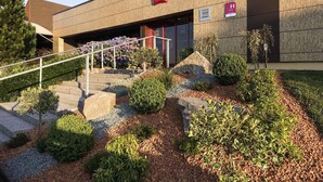 A hotel entrance with a staircase, a sign for 'Montbéliard,' and a 'H' rating sign. - ibis Montbeliard (Montbeliard)