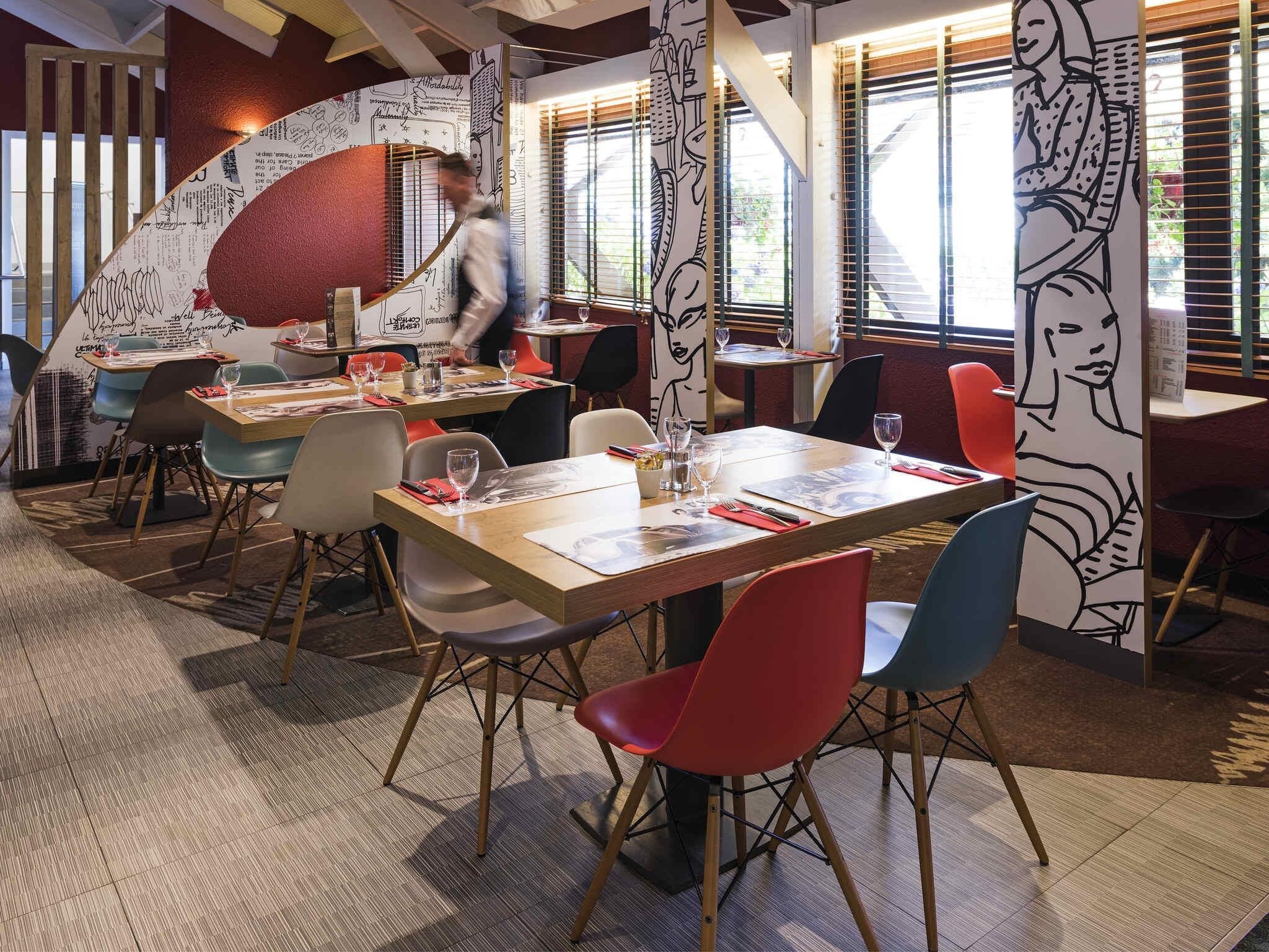 A restaurant interior with tables, chairs, and a person walking.