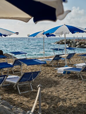 On the beach, black sand, sun-loungers, beach umbrellas