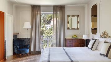 Camera d'albergo con un letto grande, una poltrona, una cassettiera e uno specchio.