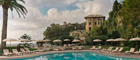 Una piscina al aire libre de temporada, sombrillas, tumbonas