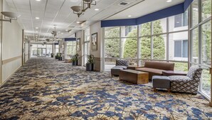 A hotel lobby with a patterned carpet, seating area, large windows, and ceiling lights. - Best Western Plus Coeur d'Alene Inn (Coeur d'Alene)