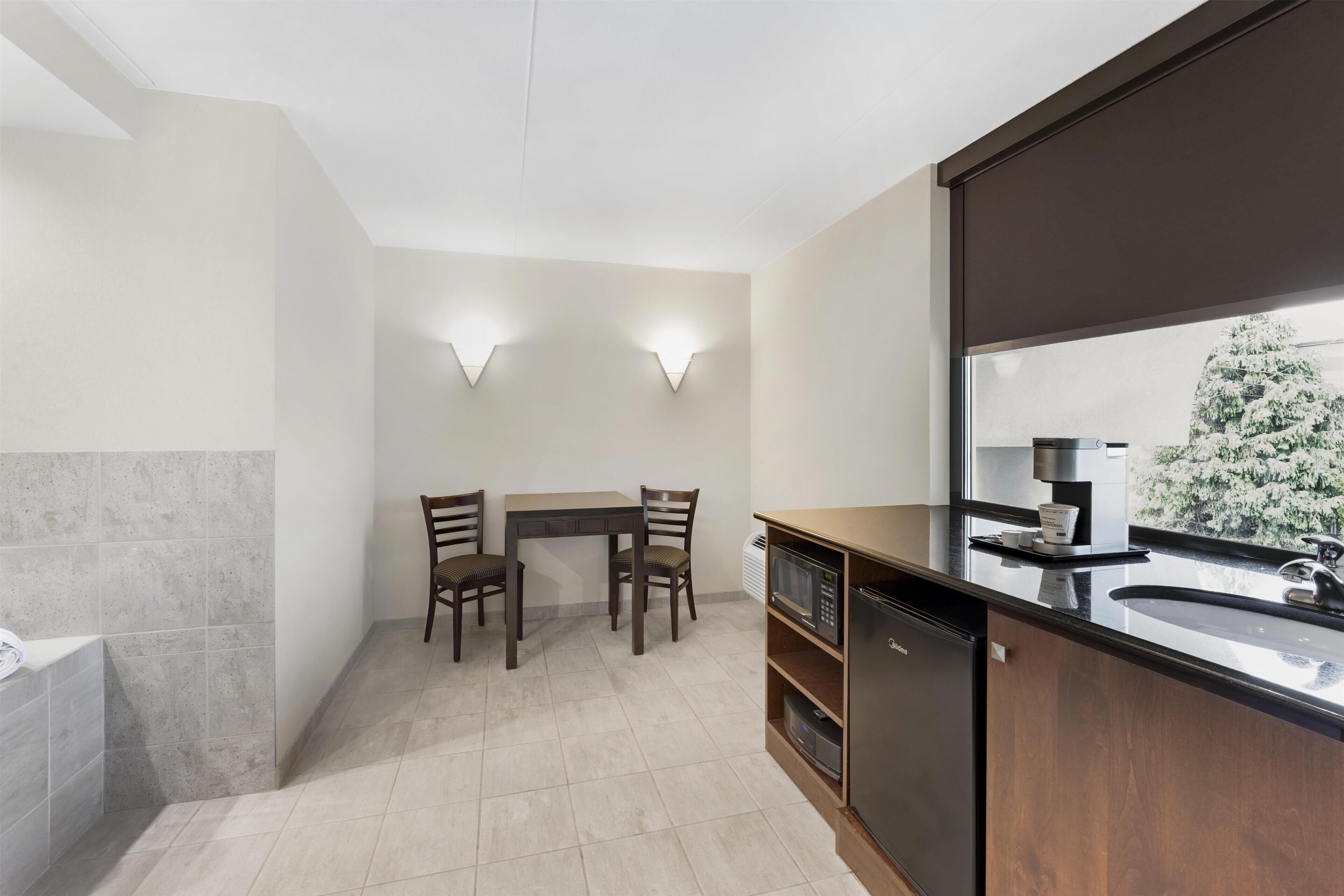 A modern kitchen with a dining area, a dishwasher, and a large window with a view of trees.