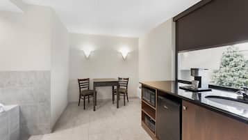 A modern kitchen with a dining area, a dishwasher, and a large window with a view of trees.