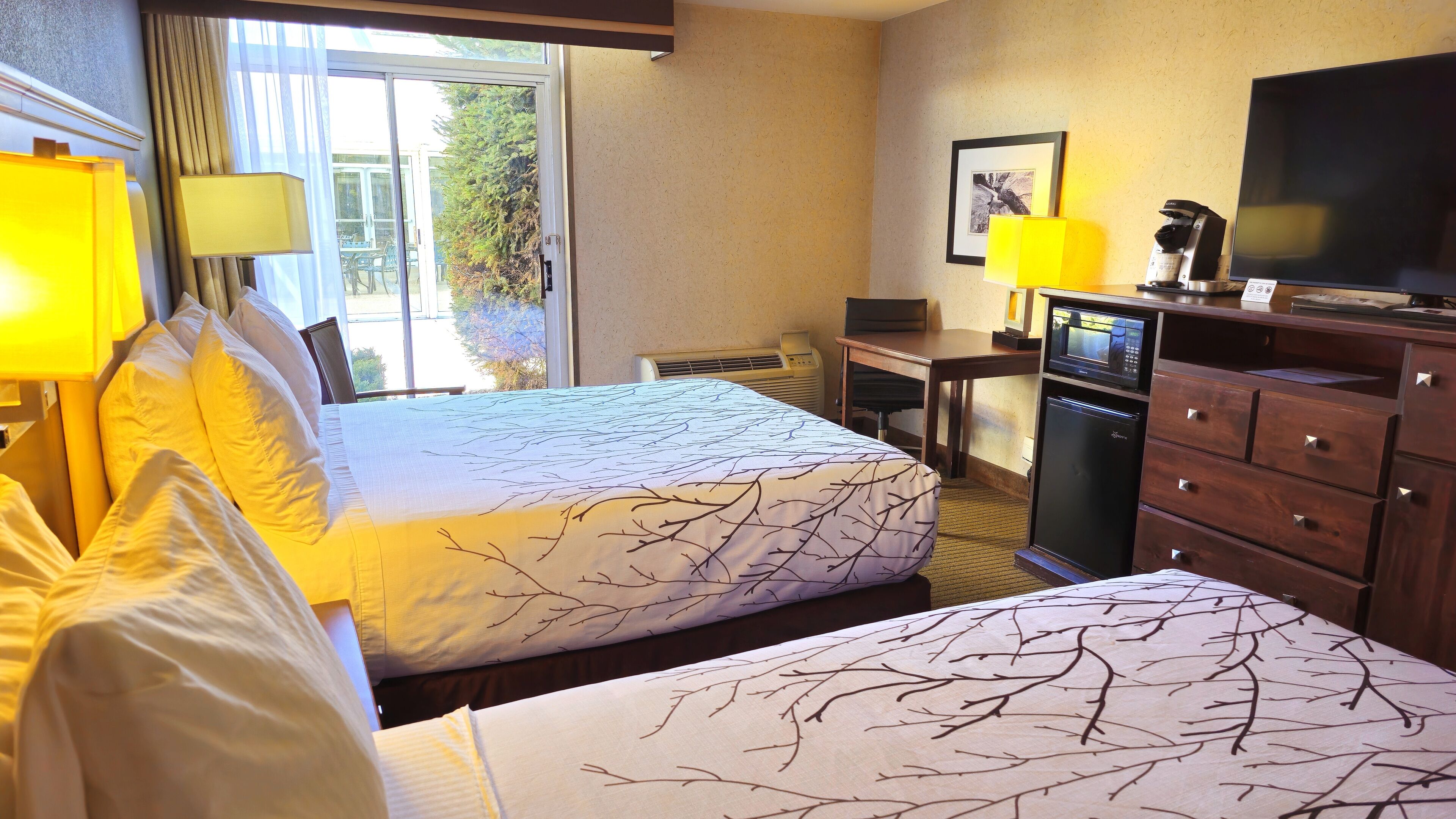 Una habitación de hotel con cama, escritorio, televisor y refrigerador.