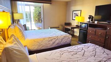 Una habitación de hotel con cama, escritorio, televisor y refrigerador.