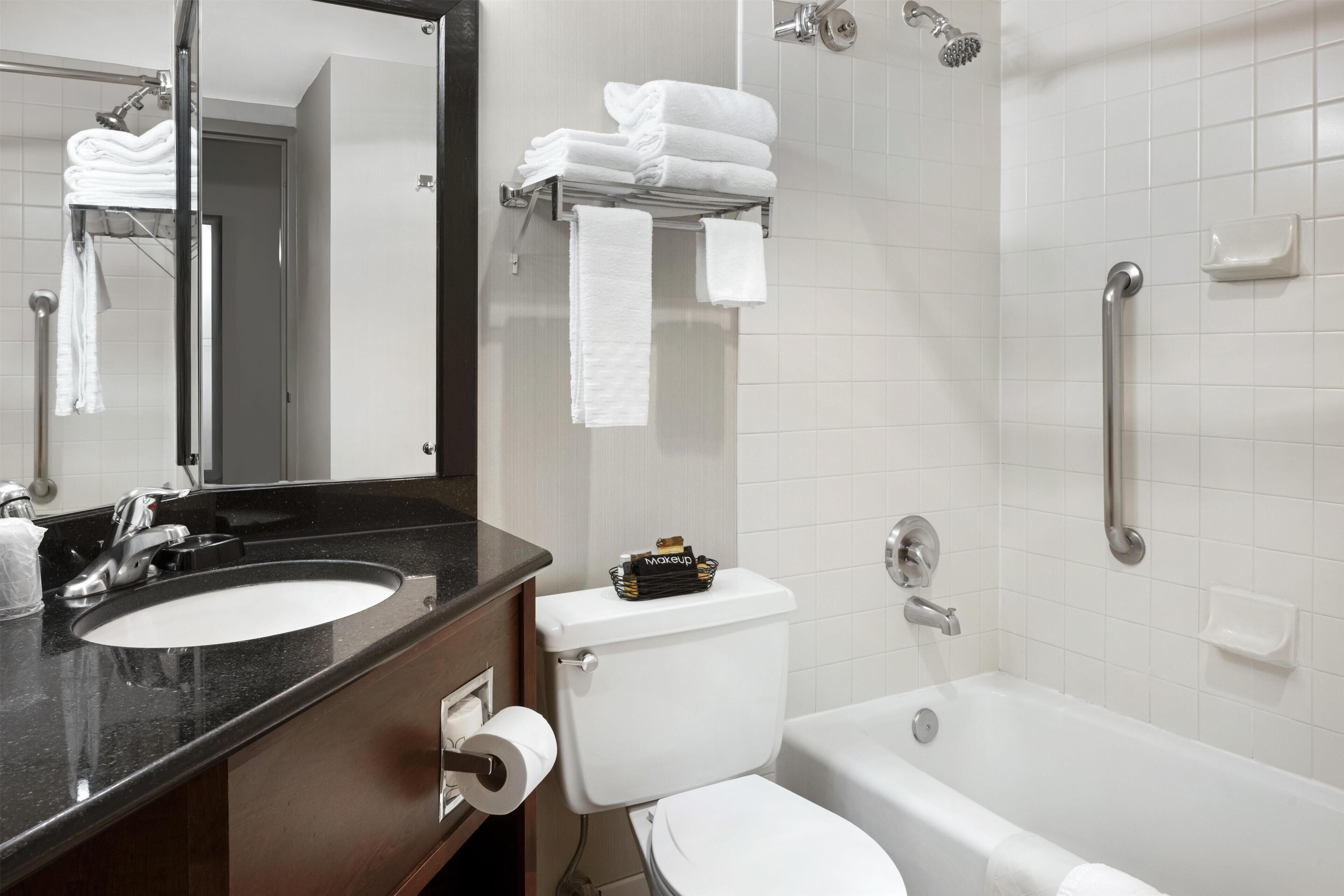 A bathroom with a sink, toilet, and bathtub. There are towels on a rack and a mirror above the sink.