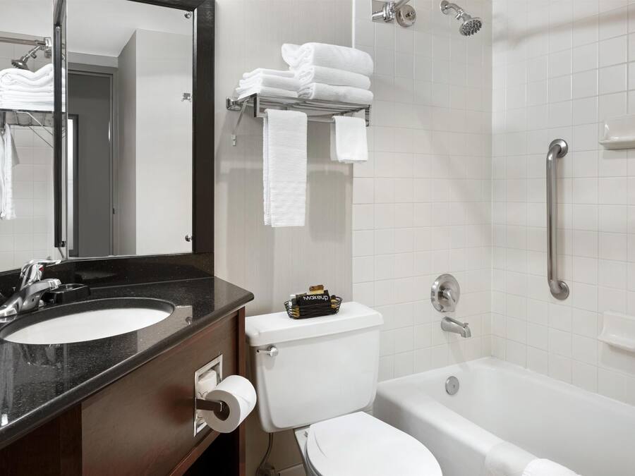 A bathroom with a sink, toilet, and bathtub. There are towels on a rack and a mirror above the sink.