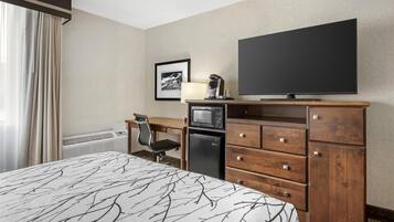 Hotelkamer met een bed, een bureau met stoel, een televisie, een magnetron en een koelkast.