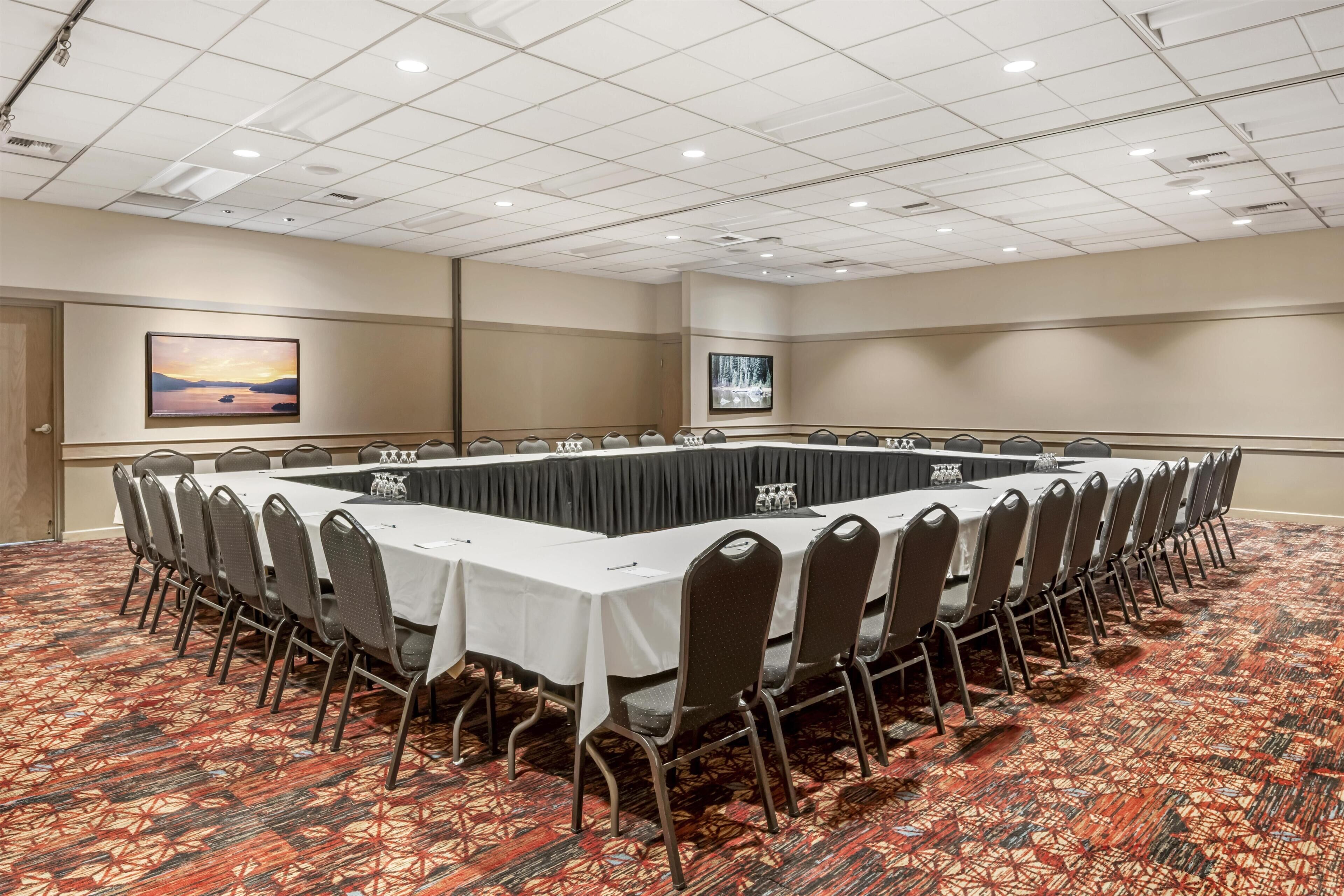 A conference room with a long table, chairs, and carpeted floor.