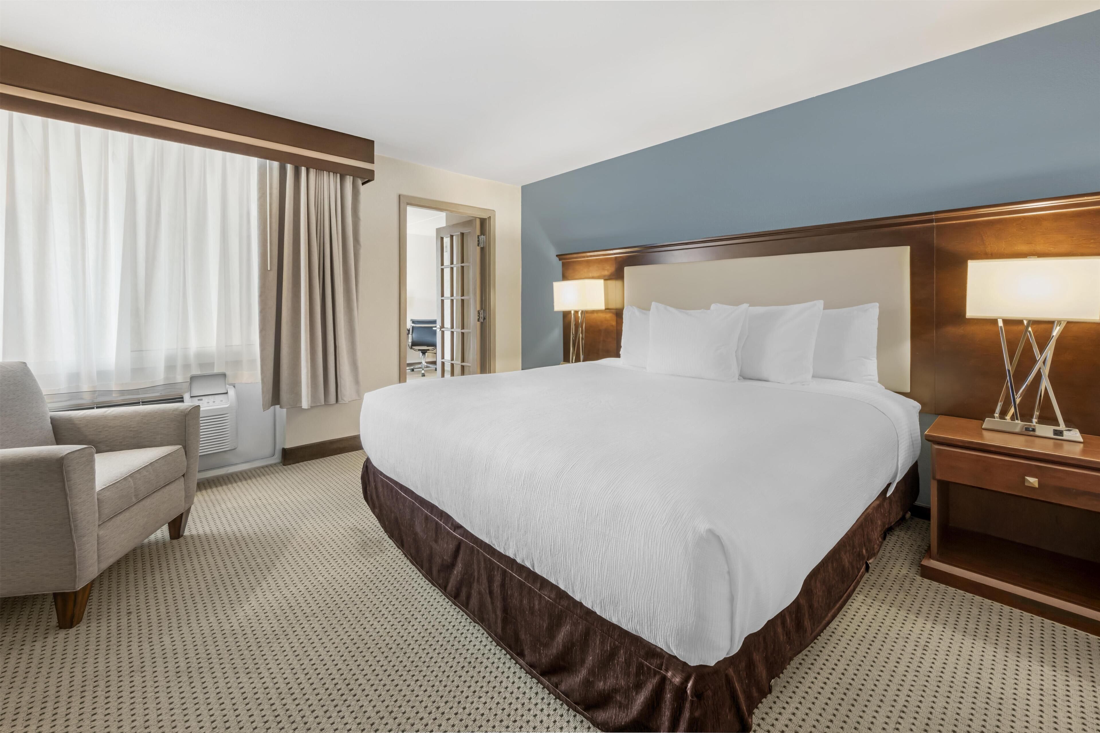 Een hotelkamer met een groot bed, een stoel, een bureau en een lamp.