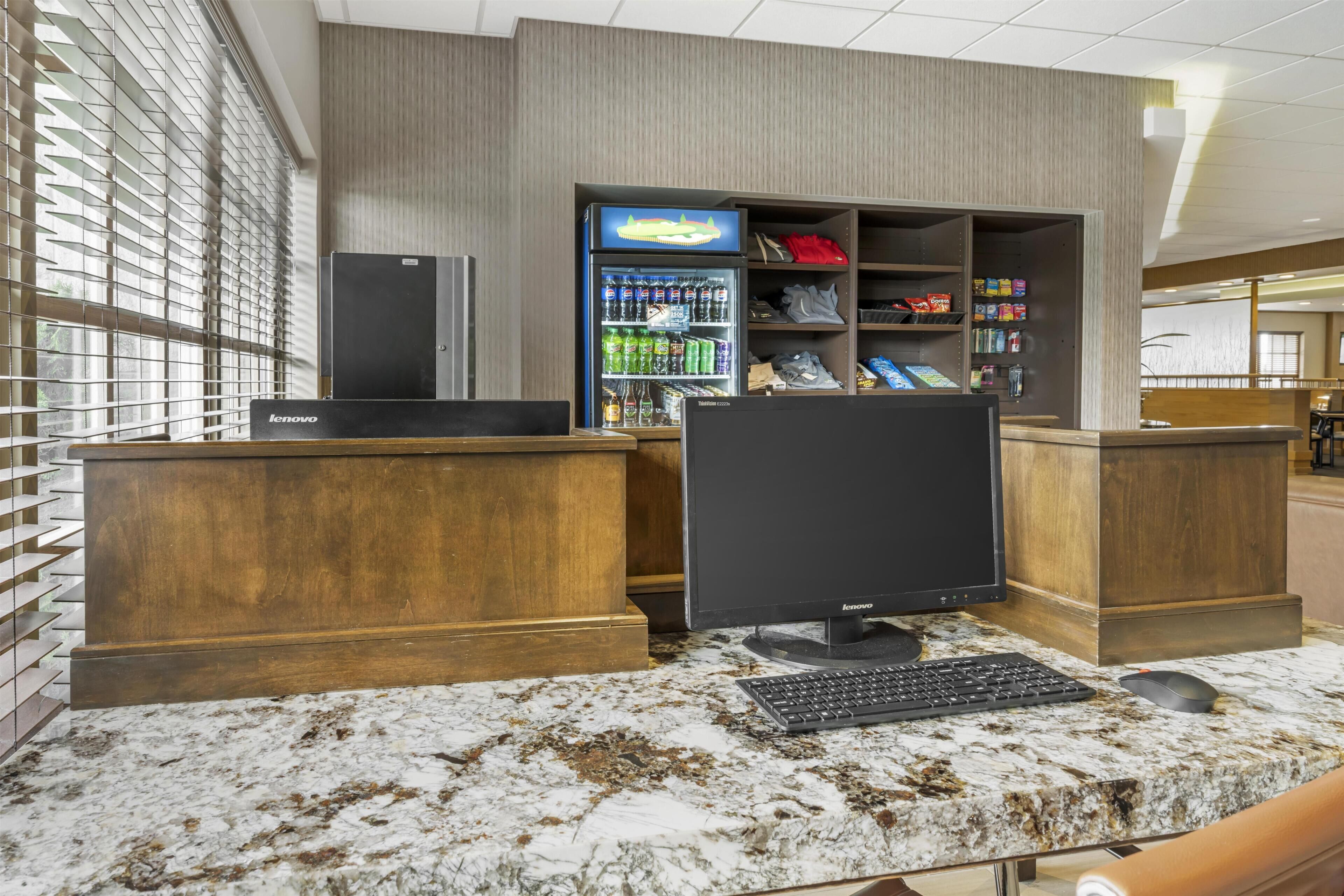 A reception desk with a computer, a beverage dispenser, and a shoe display.