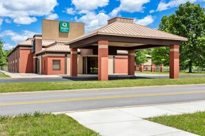 A Quality Inn with a red and beige exterior, a covered entrance, and a parking lot.