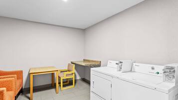 Une buanderie équipée d’un lave-linge, d’une table et d’une chaise.