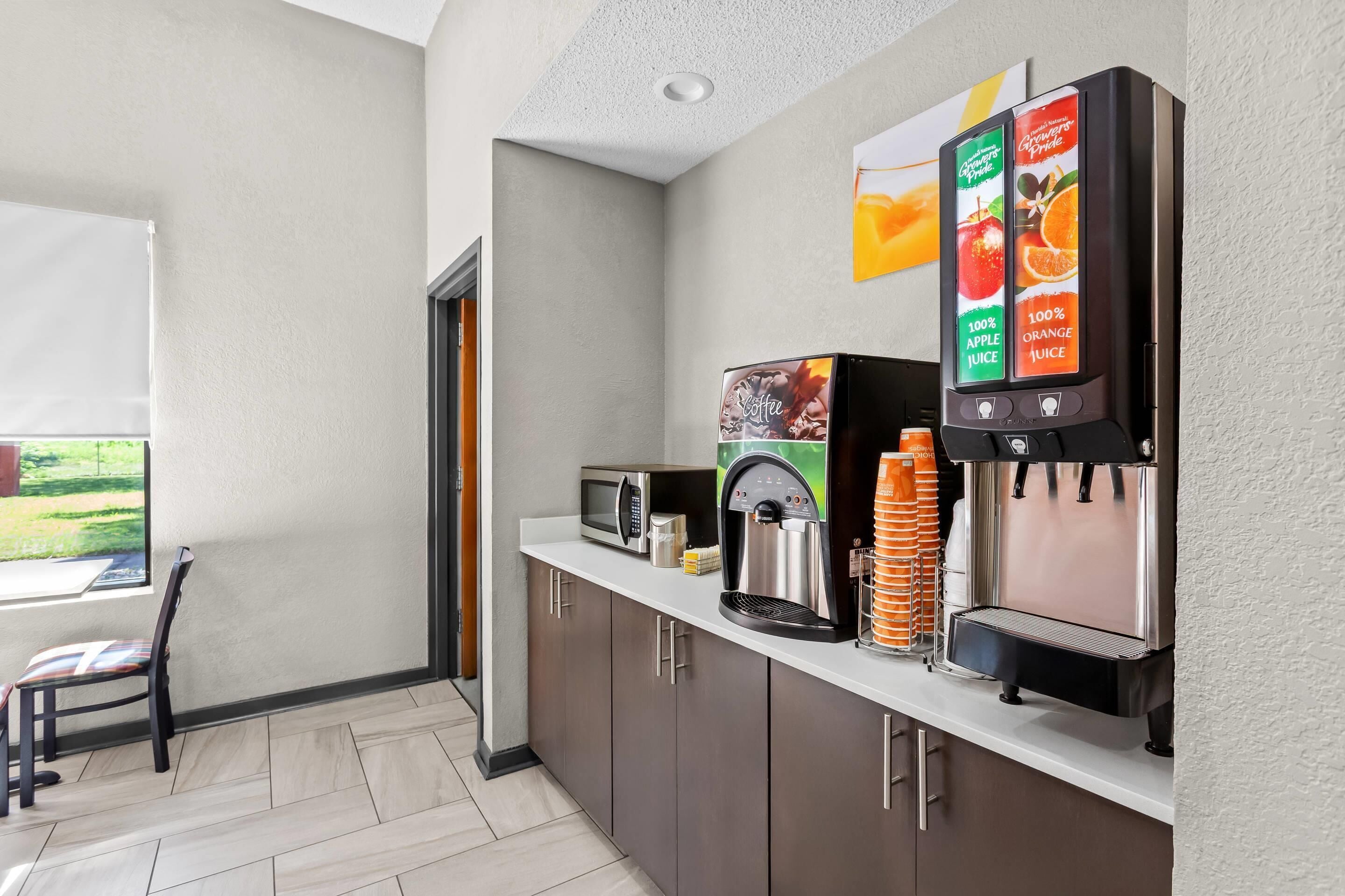 Una kitchenette con cafetera, microondas y dispensador de jugo.