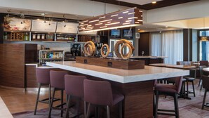 A modern bar area with a marble counter, bar stools, and a television screen.