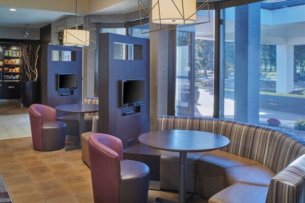 A modern interior with a round table, cushioned seating, and a television mounted on a wall.